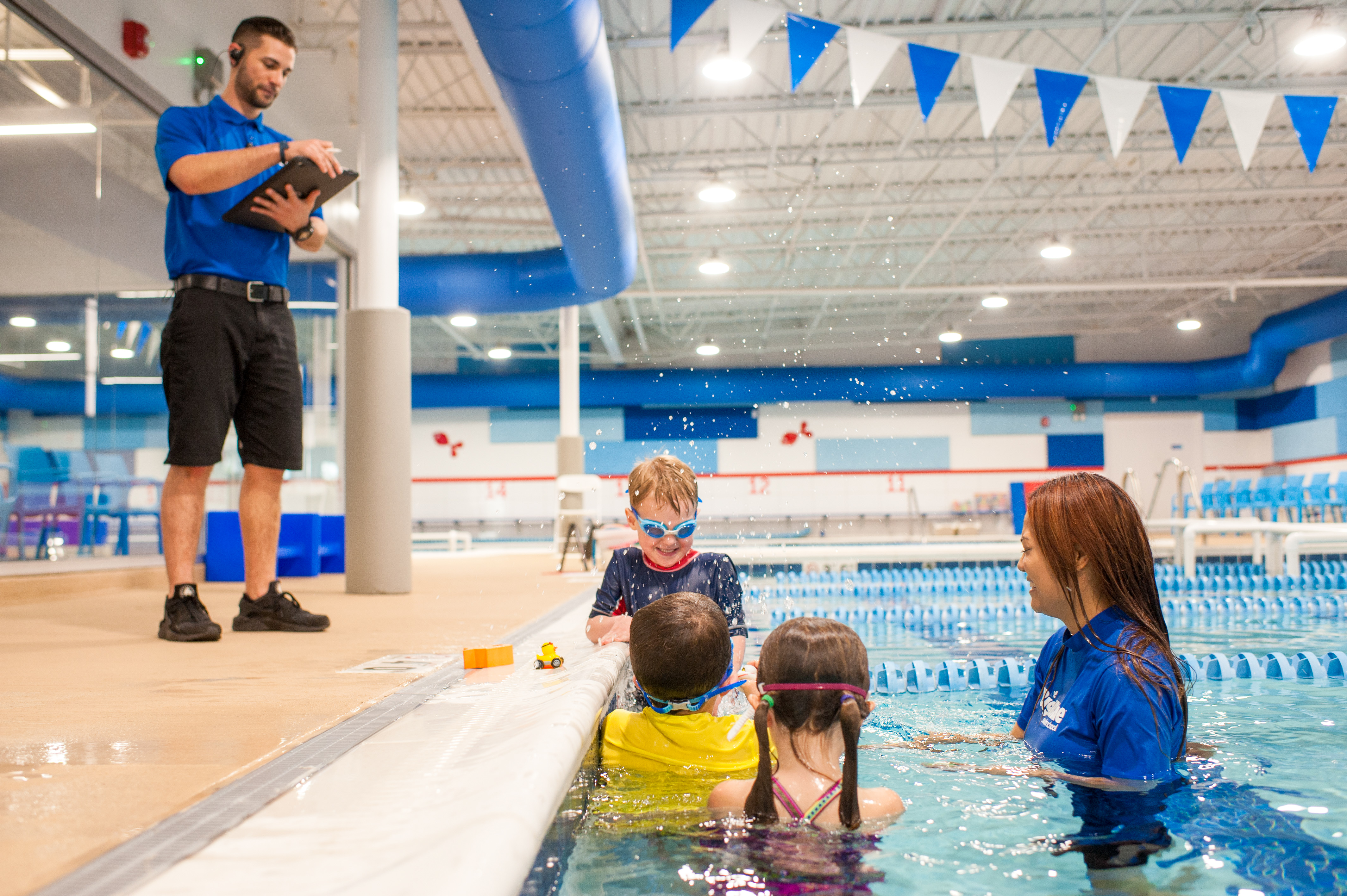 Manager tracks progress while during fun swimming lesson for kids