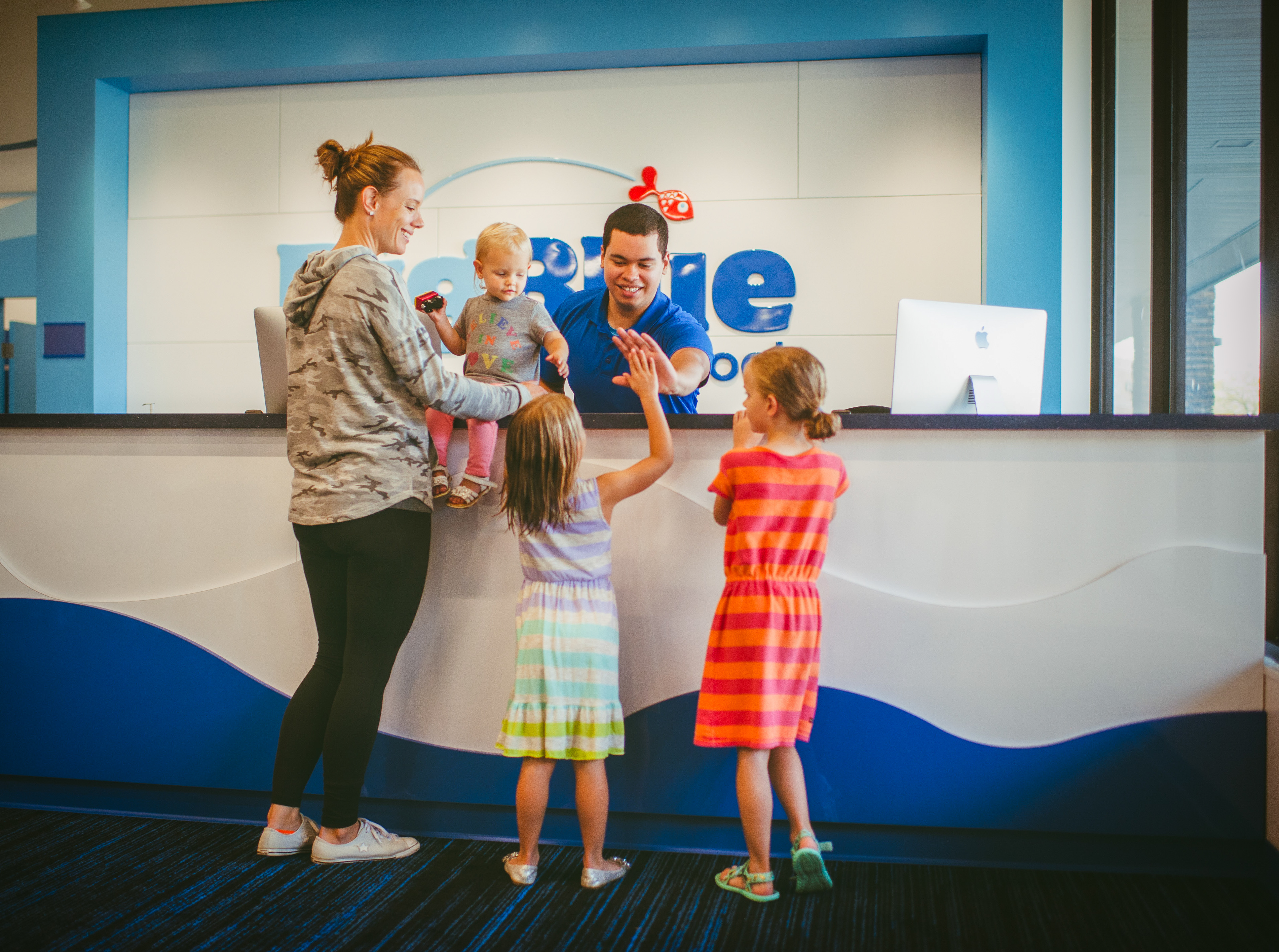Big Blue Swim School's friendly front desk staff helps a family prepare for their swimming lessons