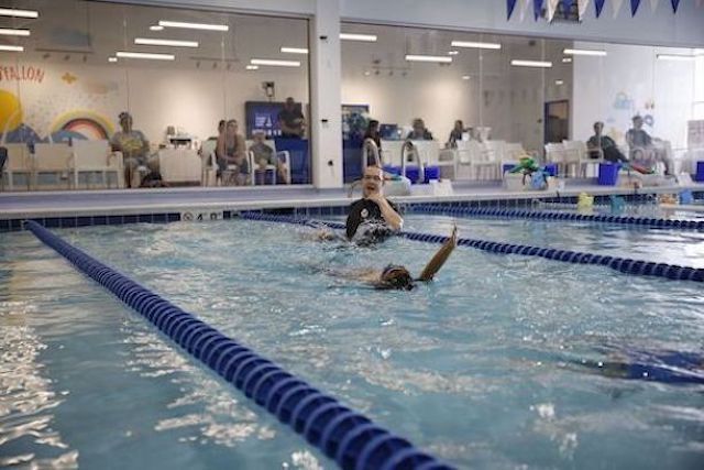 Three swimmers swim the backstroke