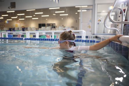 A young swimmer with goggles prepares to swim a length of the pool