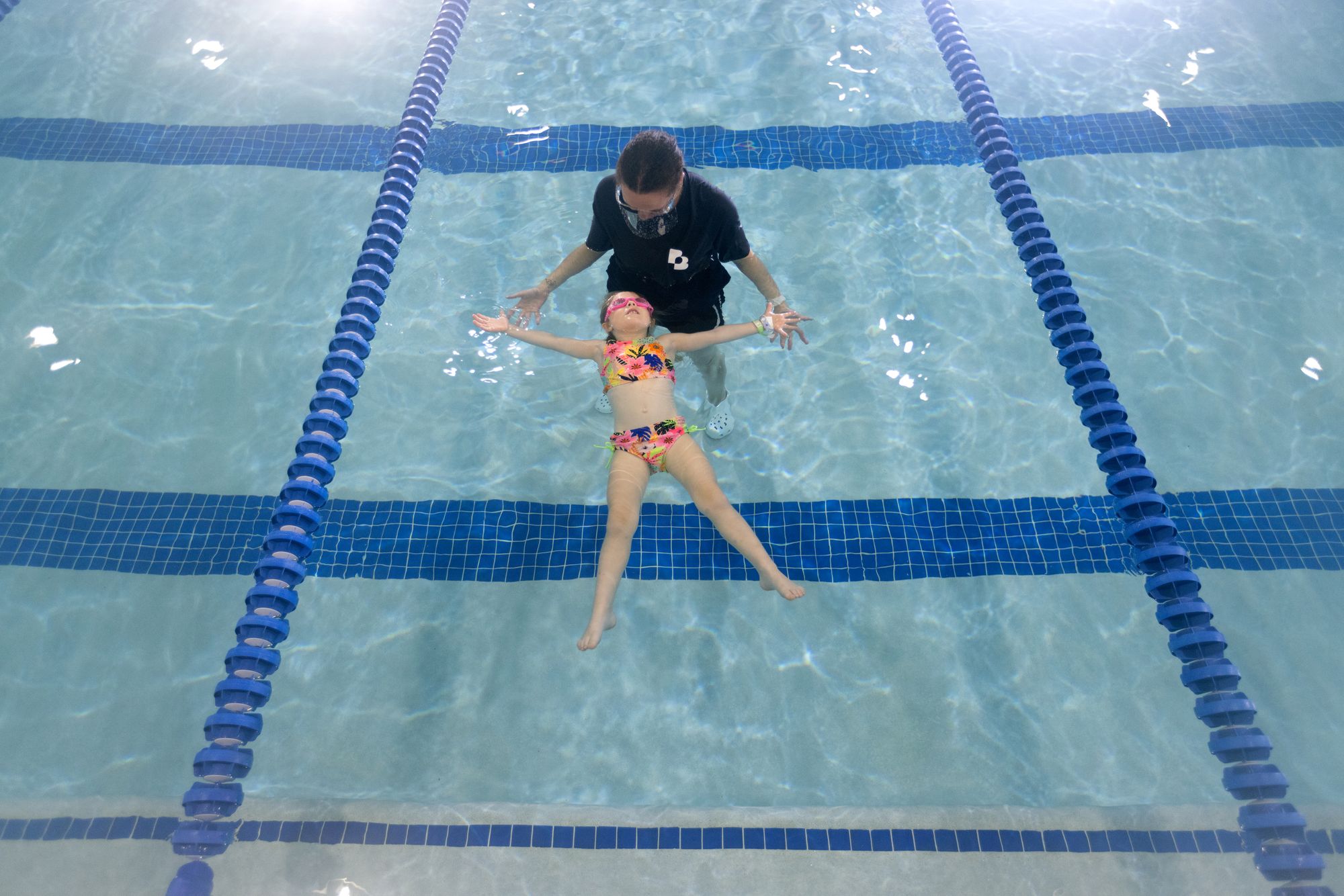 Girl practicing how to float on her back during swim lessons