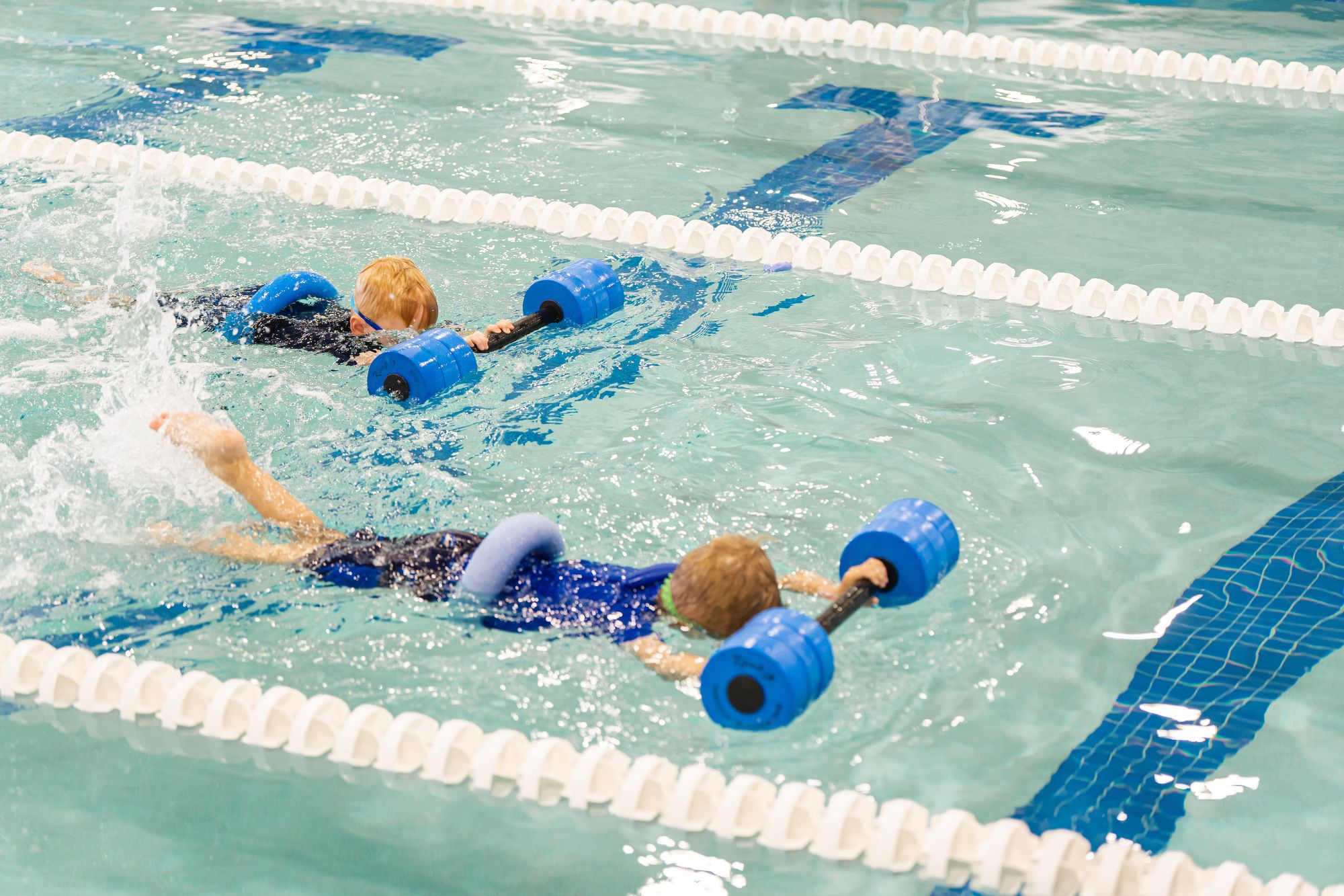 Two boys practicing proper breathing techniques during swim lessons