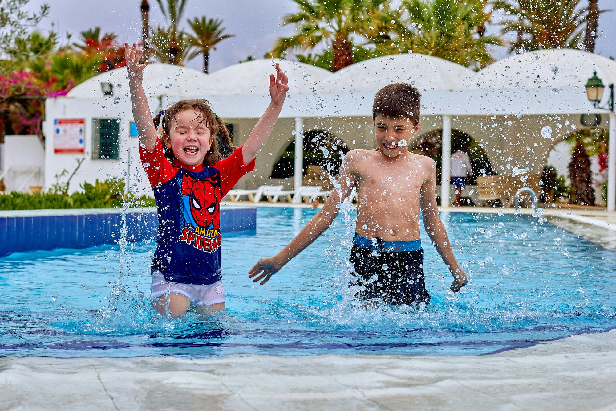 Two children splashing in the swimming pool together