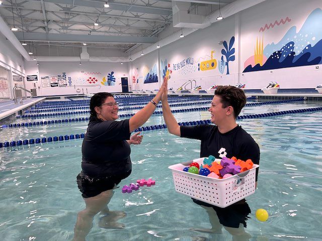 Brooke and another team member high fiving in the pool