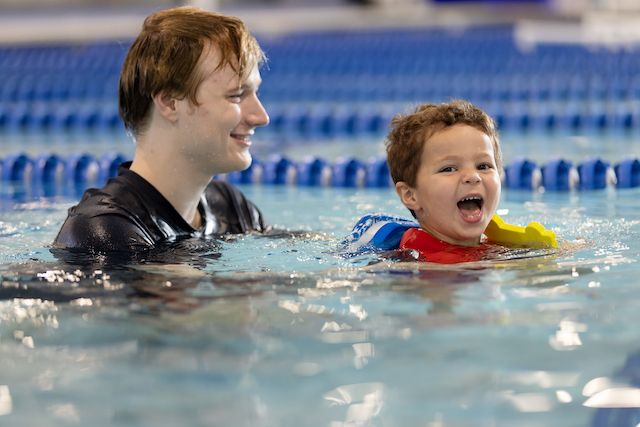 Smiling child and instructor in the pool