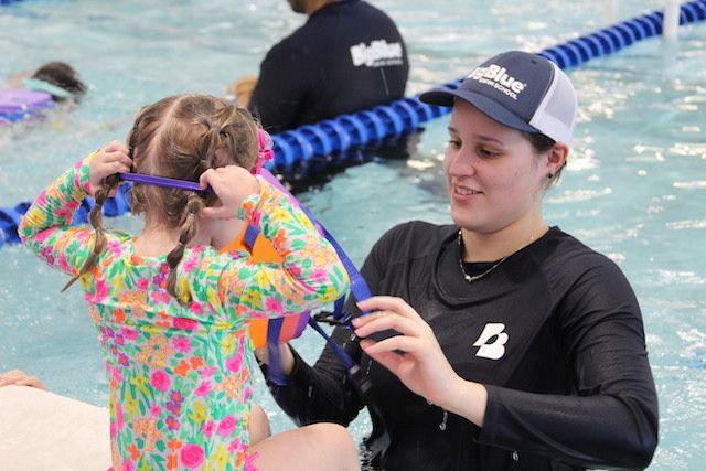 Yasmin helping a student put her swim gear on at the pool deck