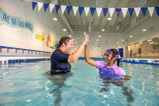 Big Blue swim instructor and student high five in the pool