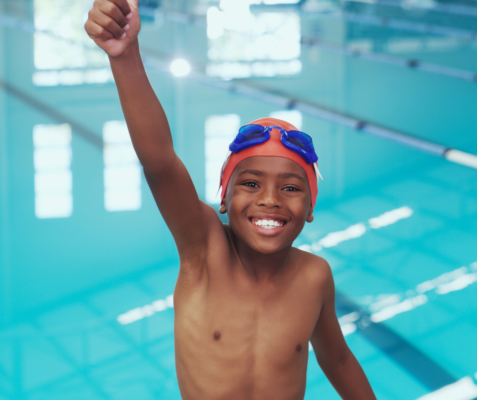 Young swimmer at pool raises arm in celebration