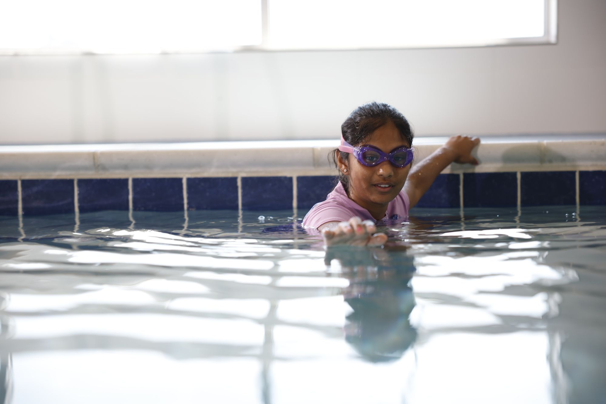 A young, experienced Big Blue swimmer prepares to practice her streamline during a swim lesson