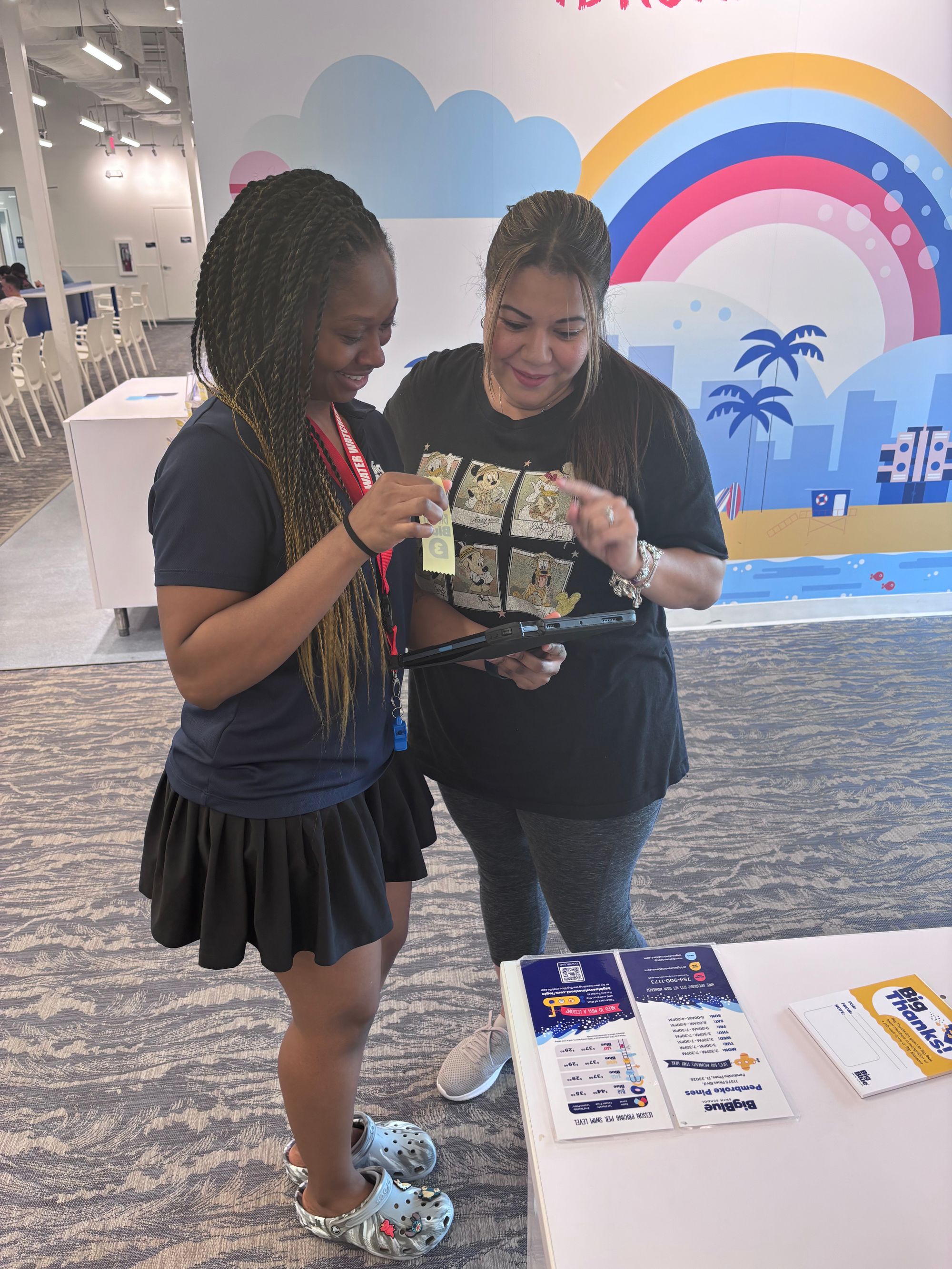 Deck Supervisor, Chanele, talks to a parent of a Big Blue swimmer, explaining the swimmer's progress