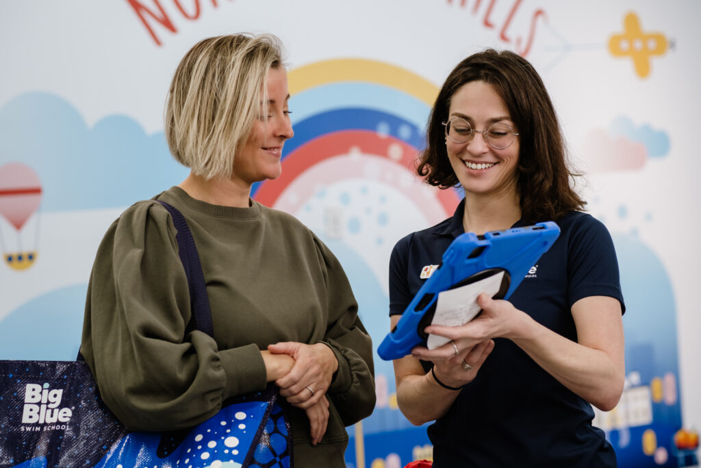 big blue staff member helping a mom to schedule lessons