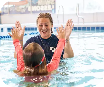 Swim instructor high-fiving a young girl during a swim lesson