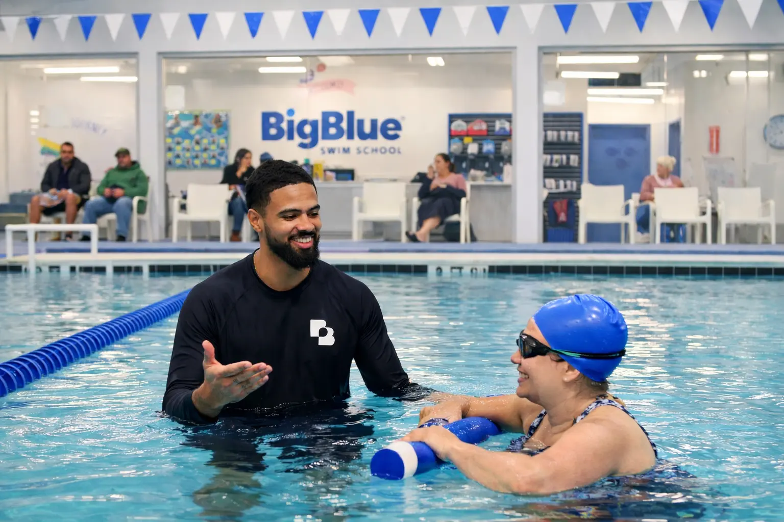 a Big Blue Swim School instructor smiling and teaching a adult swim lesson class