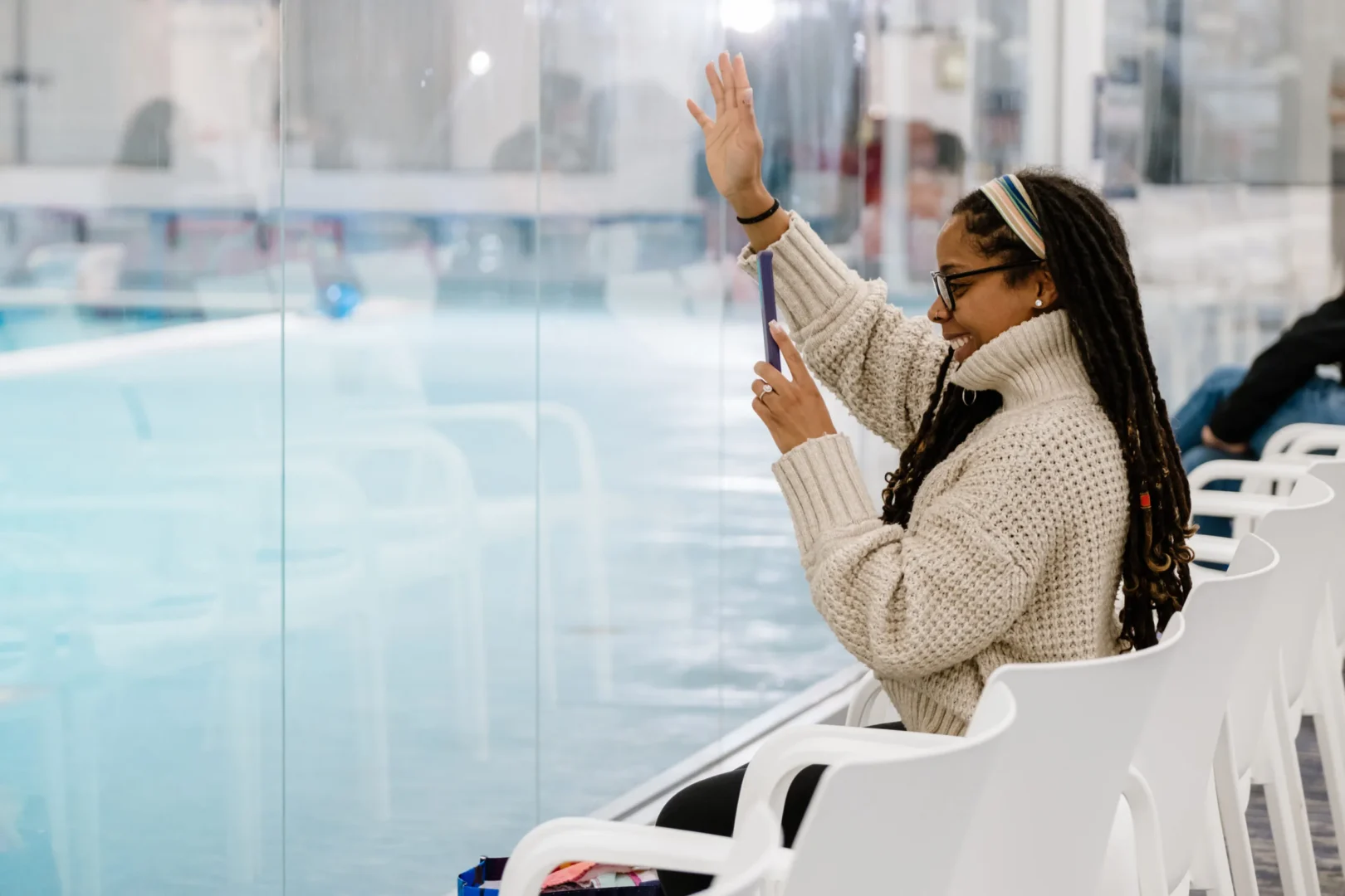a lady waving and facing the window of a Big Blue Swim School pool